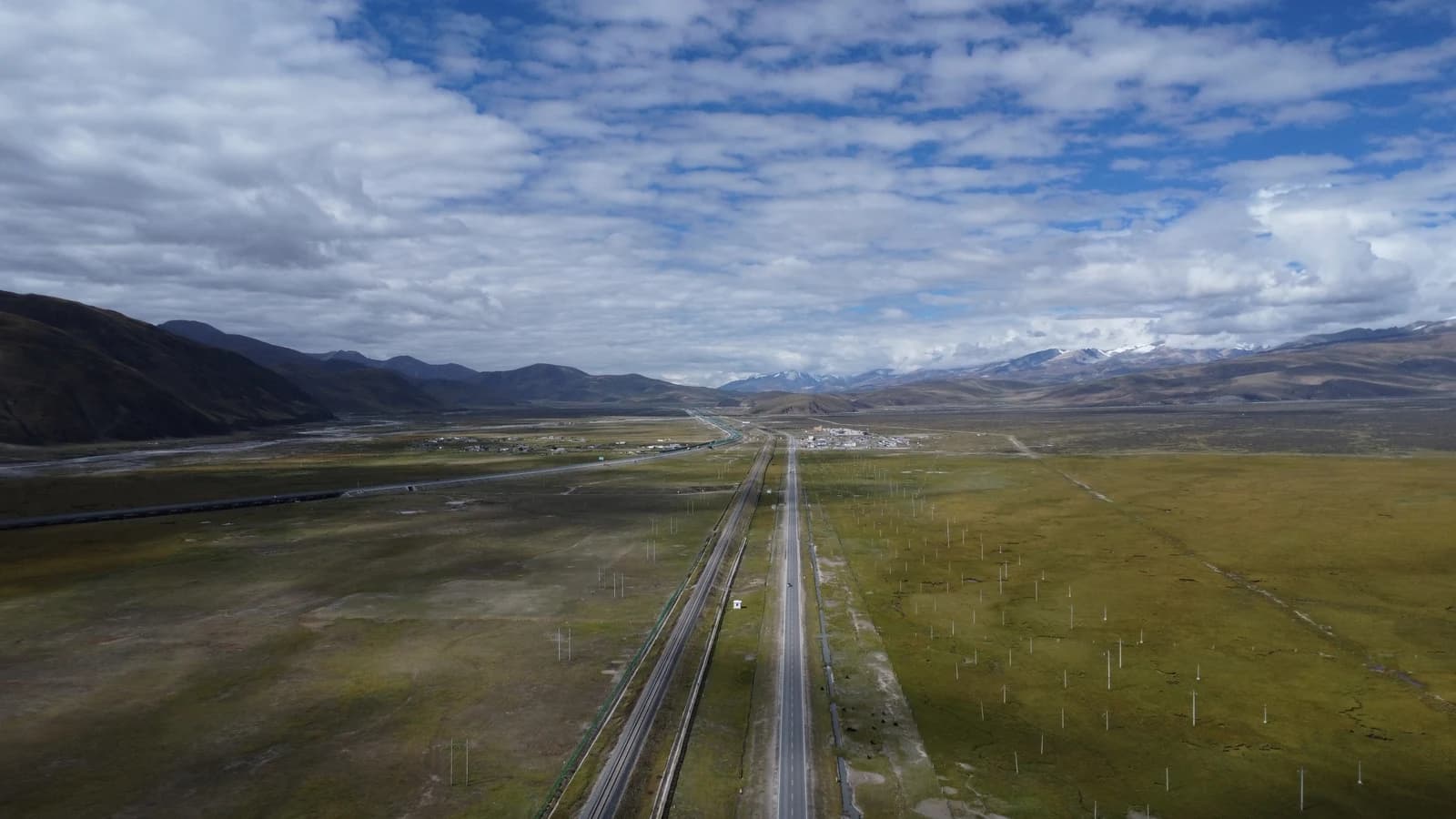 Endless high-altitude plateau highway under cumulus clouds
